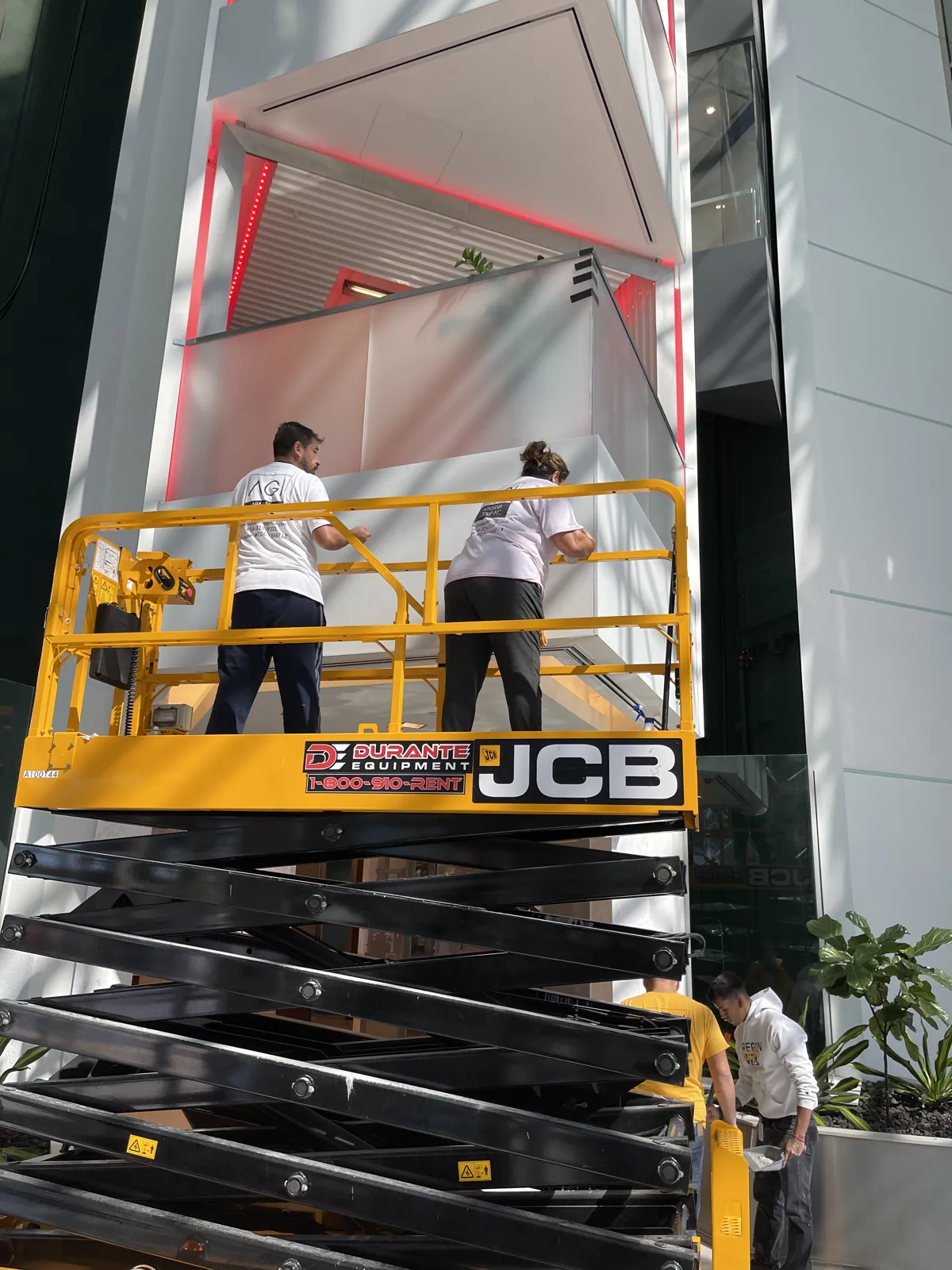 Apadana Group Inc. crew working from a scissor lift on a commercial office atrium wall