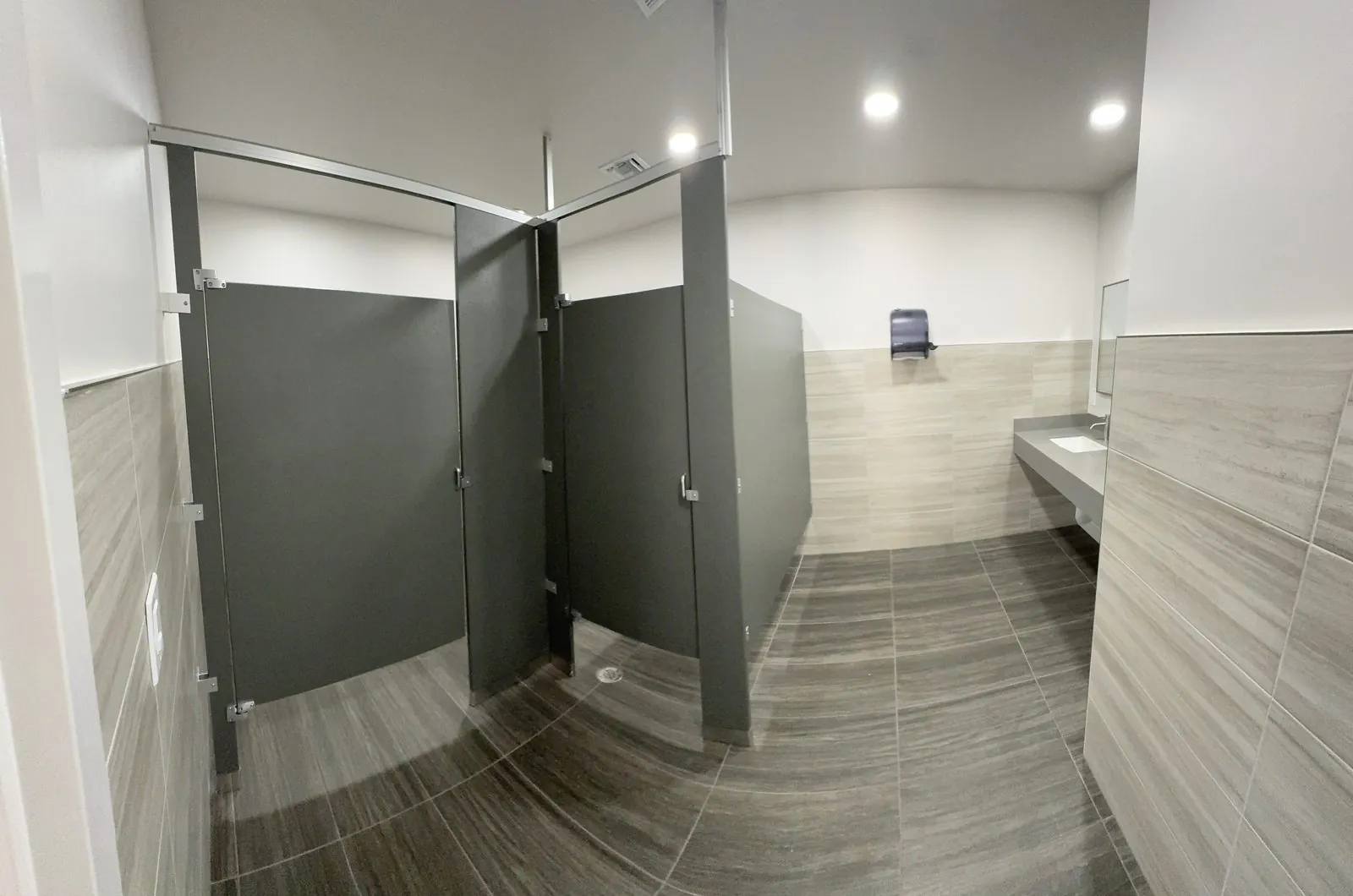 Commercial restroom stalls with gray toilet partitions and tile floor