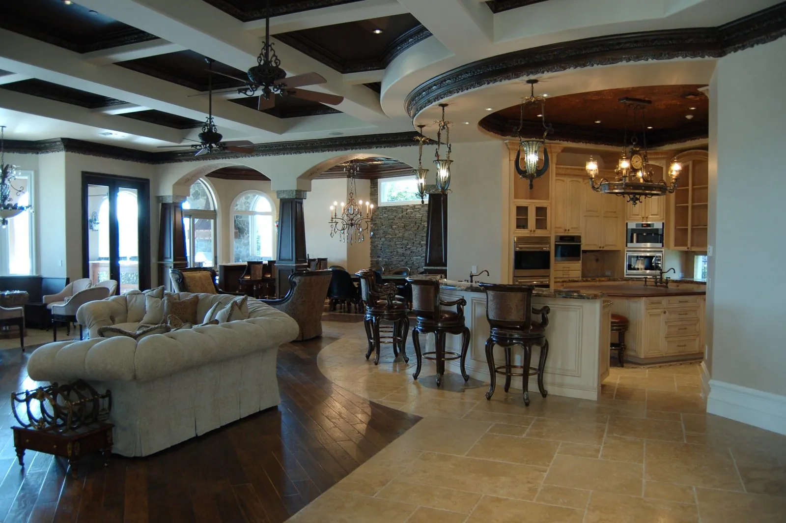 Open living room and kitchen with coffered ceiling and arched windows