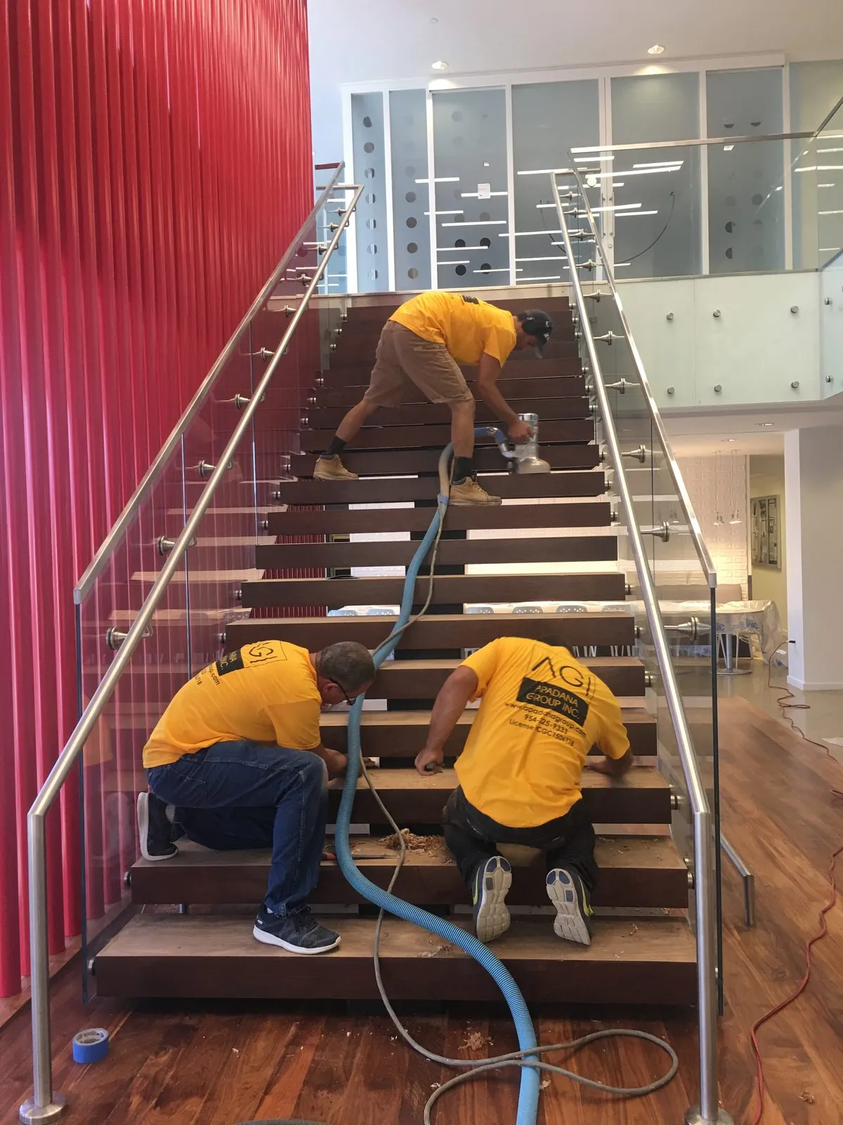 Apadana Group Inc. crew refinishing wood stair treads in a commercial office