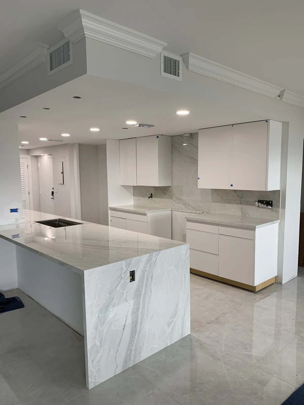Kitchen with white flat-panel cabinets and a marble-look waterfall island