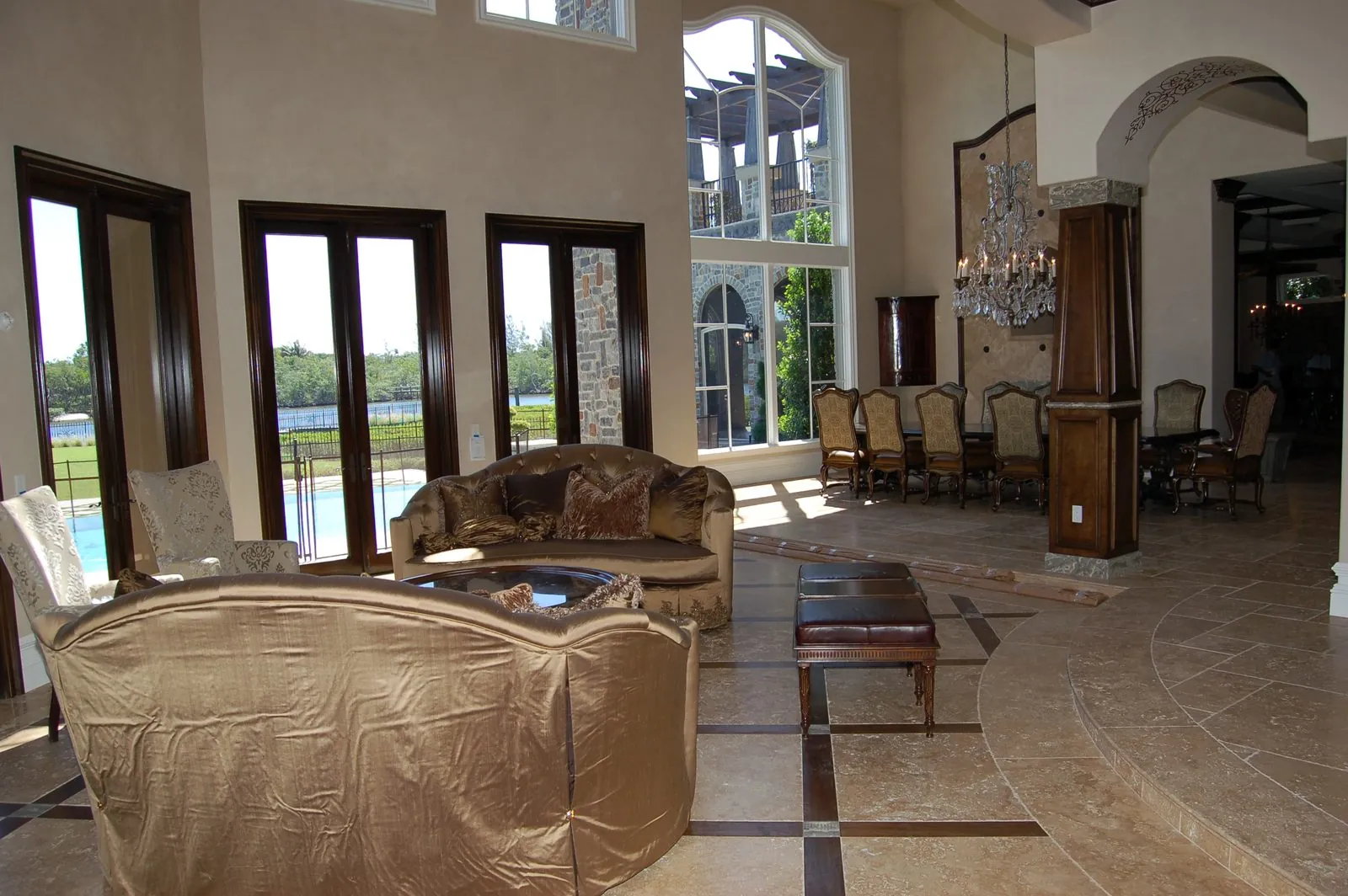 Two-story great room with arched windows, chandelier, and tile flooring