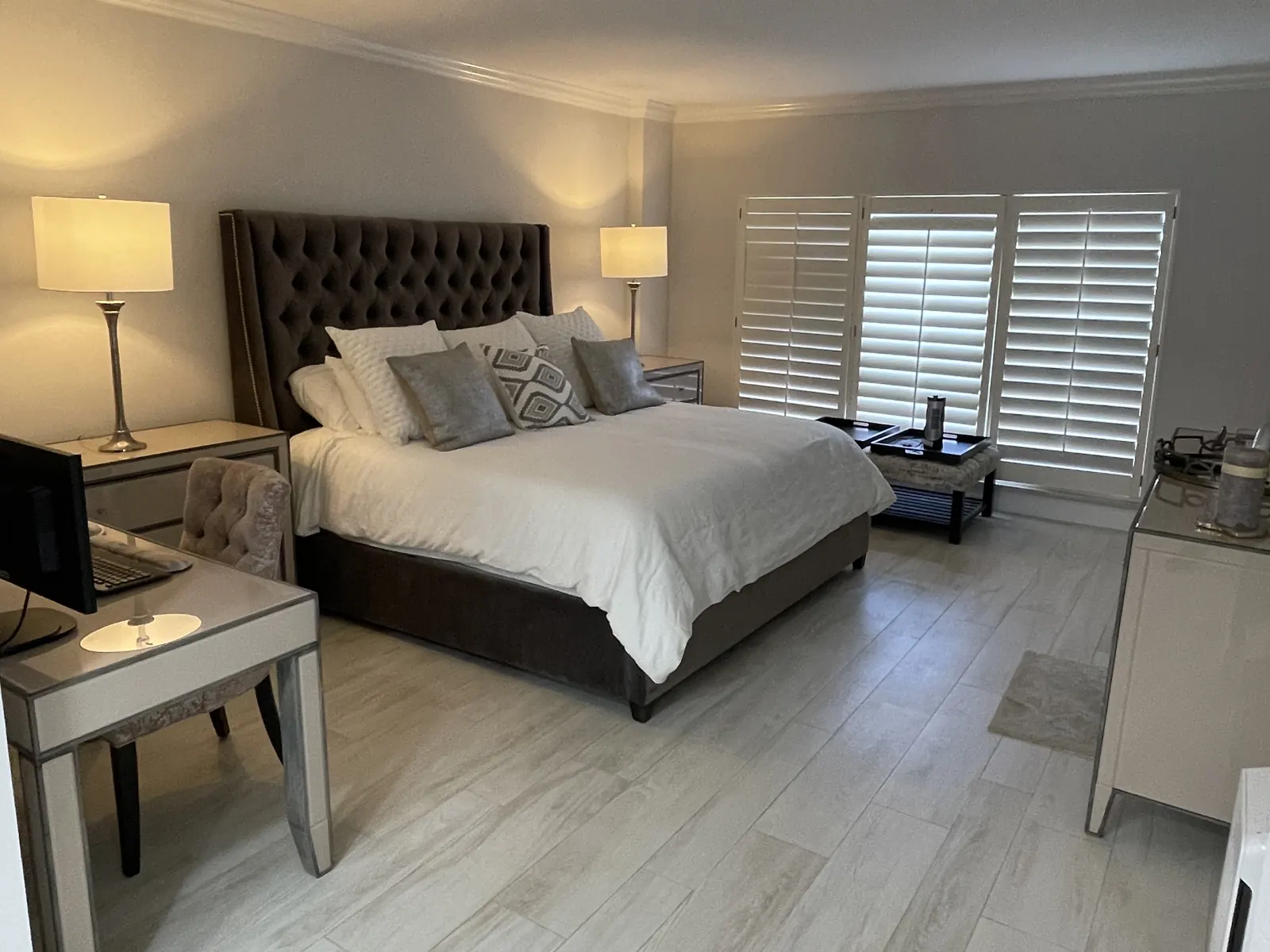 Renovated primary bedroom with wood-look floor tile, plantation shutters and crown molding by Apadana Group Inc.